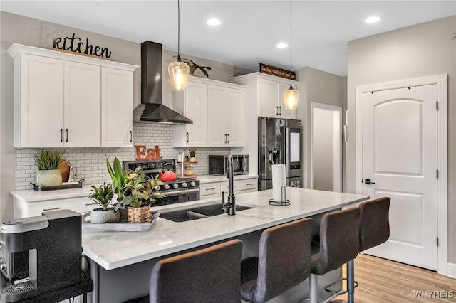 kitchen with wall chimney exhaust hood, tasteful backsplash, white cabinetry, a breakfast bar, and appliances with stainless steel finishes