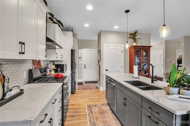 kitchen featuring a sink, white cabinetry, gray cabinetry, range hood, and appliances with stainless steel finishes