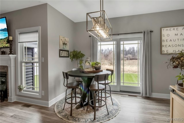 dining space featuring light wood-type flooring, plenty of natural light, baseboards, and visible vents