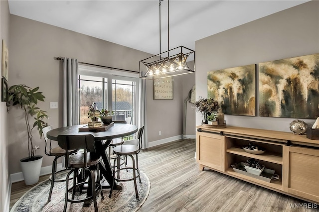 dining space featuring baseboards, an inviting chandelier, and light wood-style flooring