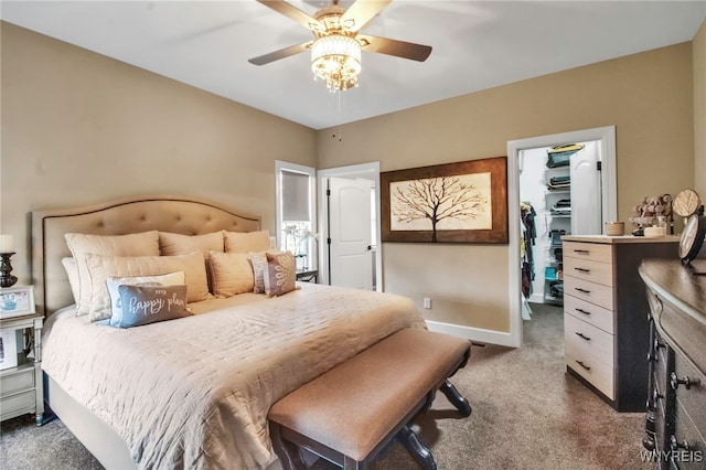 carpeted bedroom with a closet, a spacious closet, a ceiling fan, and baseboards