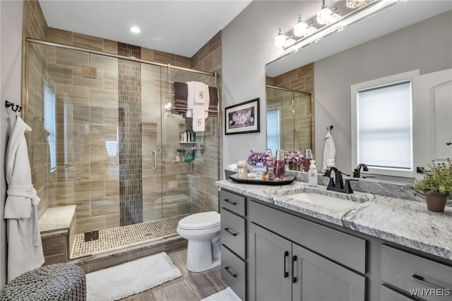 full bathroom featuring a shower stall, toilet, vanity, and wood finished floors