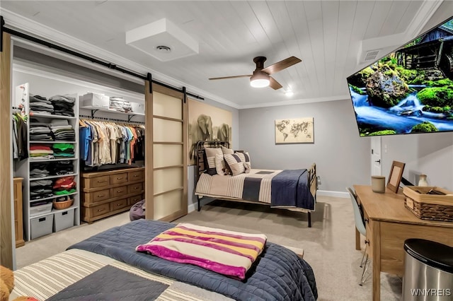 bedroom with a barn door, a ceiling fan, light colored carpet, and ornamental molding
