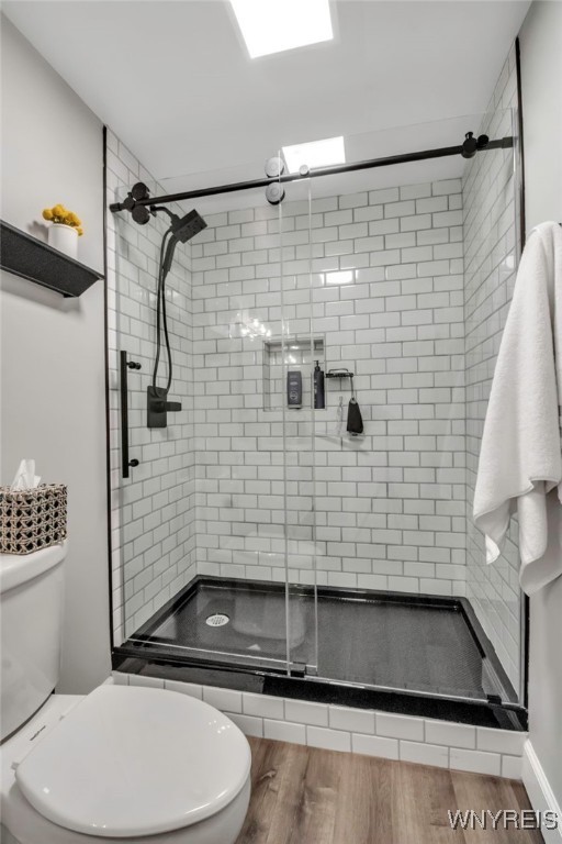 bathroom featuring a shower stall, toilet, and wood finished floors