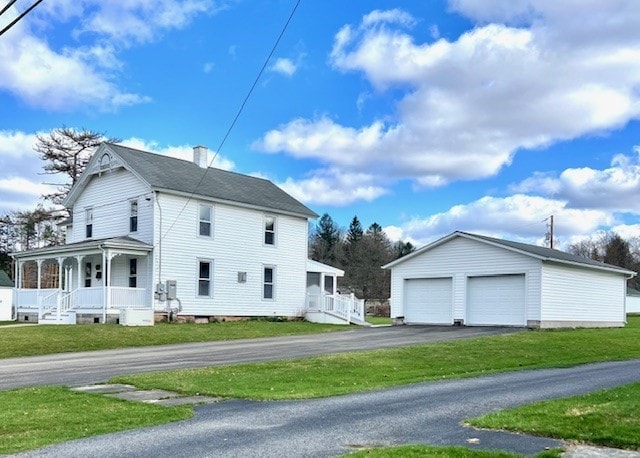 view of home's exterior featuring a chimney, an outdoor structure, a porch, a yard, and a garage