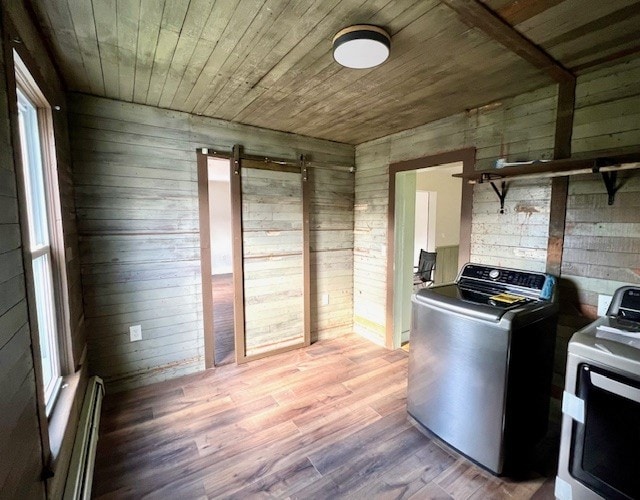 interior space featuring a barn door, wood walls, independent washer and dryer, wood ceiling, and a baseboard radiator