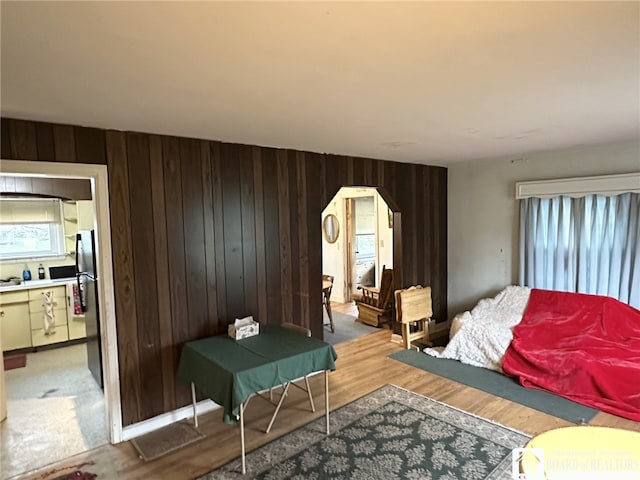 bedroom featuring wooden walls, light wood-type flooring, and multiple windows