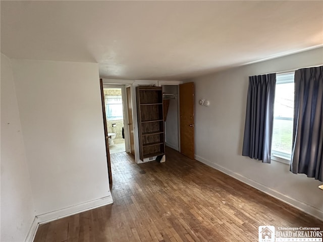 empty room with baseboards, plenty of natural light, and hardwood / wood-style flooring