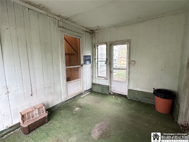 spare room with wooden walls and concrete flooring