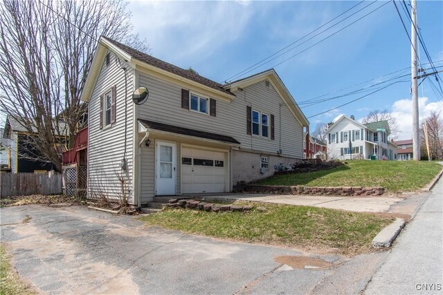 620 W St, Wilna, NY 13619 - view of front of property featuring an attached garage, aphalt driveway, fence, and a front lawn