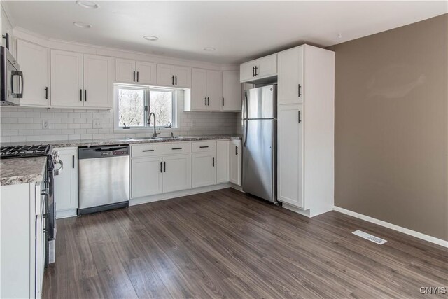 620 W St, Wilna, NY 13619 - kitchen featuring a sink, dark wood-style flooring, white cabinetry, decorative backsplash, and appliances with stainless steel finishes