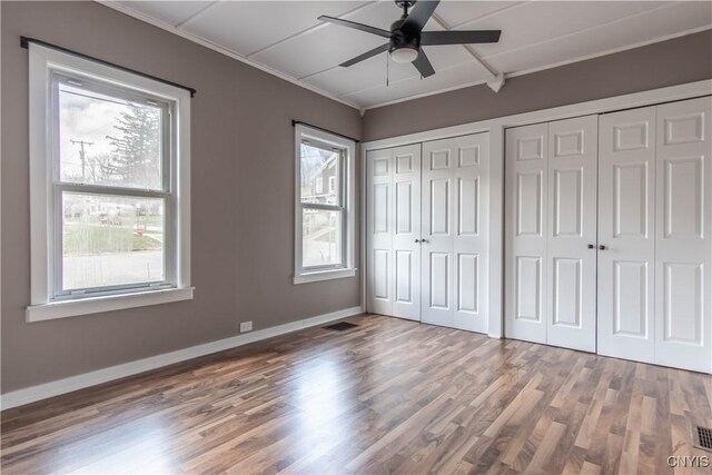 620 W St, Wilna, NY 13619 - unfurnished bedroom featuring baseboards, wood finished floors, ceiling fan, crown molding, and multiple closets
