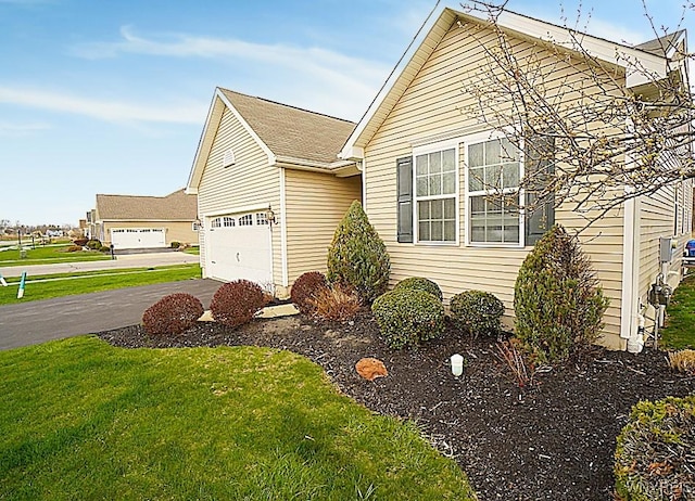 view of front of house featuring aphalt driveway, a front yard, and a garage