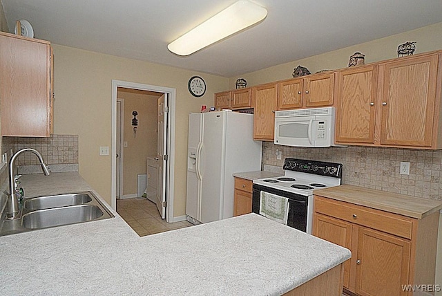 kitchen featuring a peninsula, a sink, tasteful backsplash, white appliances, and light countertops