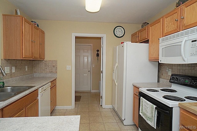 kitchen featuring tasteful backsplash, a sink, white appliances, light countertops, and baseboards