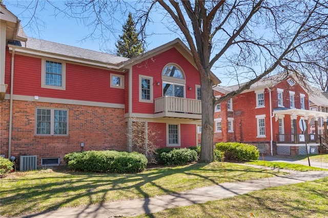 rear view of property featuring central air condition unit, brick siding, and a lawn