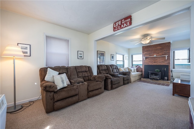 carpeted living area with a wood stove and ceiling fan