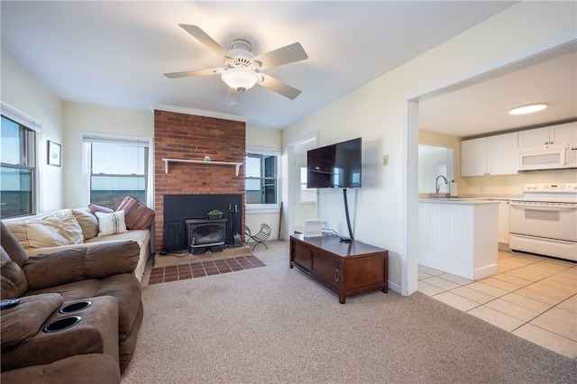 living room featuring light tile patterned floors, light carpet, a ceiling fan, and a wood stove