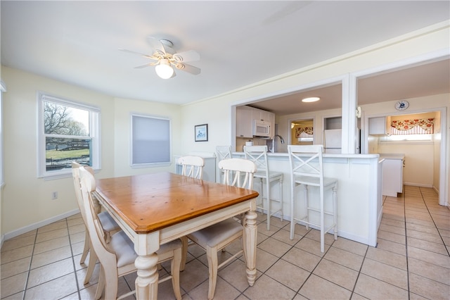 dining area featuring a ceiling fan, baseboards, a wealth of natural light, and light tile patterned floors