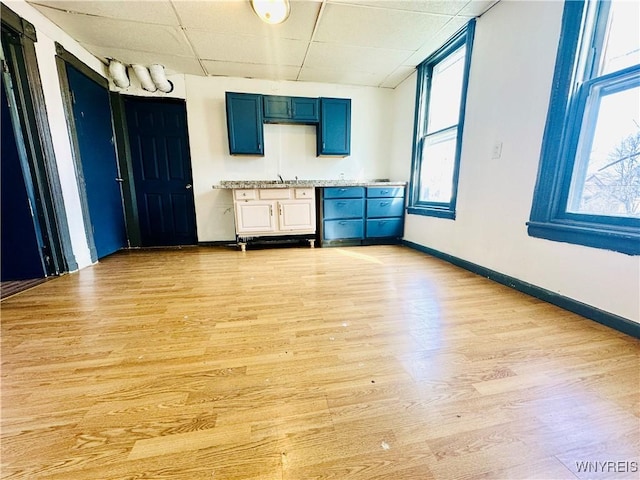 empty room featuring baseboards, light wood-style flooring, and a paneled ceiling