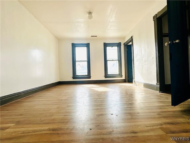unfurnished room featuring baseboards, wood finished floors, and visible vents