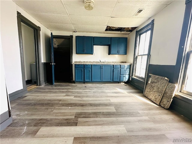 kitchen featuring light countertops, blue cabinetry, visible vents, and light wood-style floors