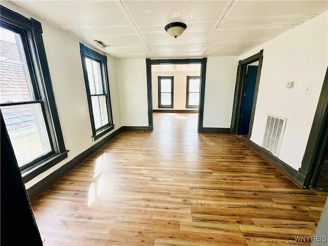 spare room featuring visible vents, baseboards, a wealth of natural light, and light wood-type flooring