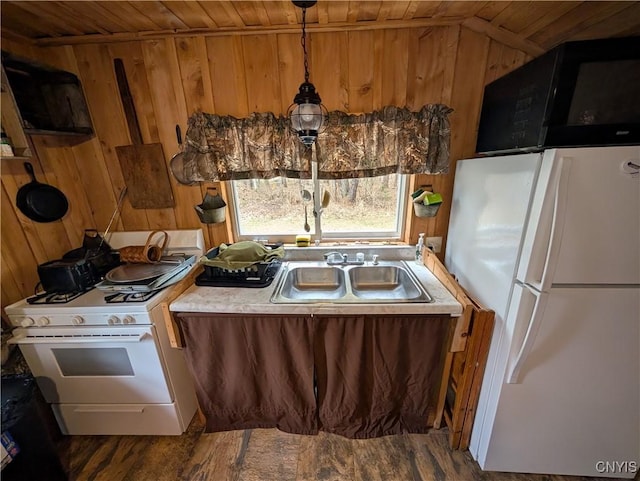 kitchen featuring wood walls, wood finished floors, wooden ceiling, a sink, and white appliances