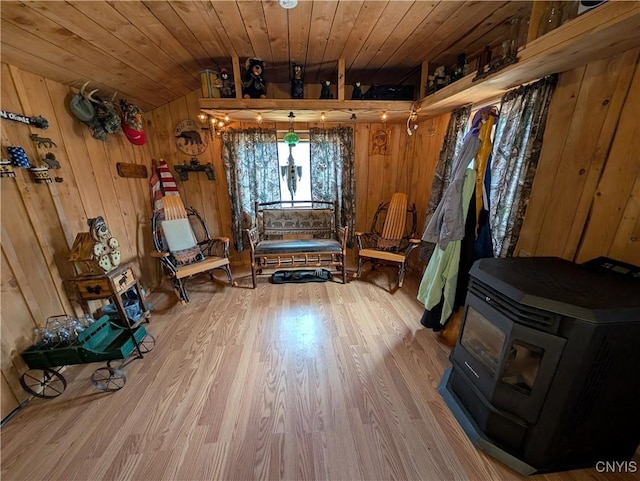 interior space with wooden ceiling, a wood stove, wood finished floors, and wooden walls
