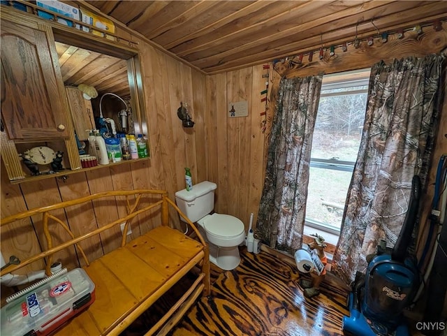 bathroom with wood ceiling, wood walls, and toilet