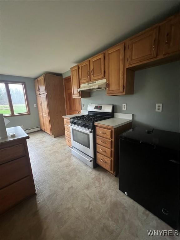 kitchen featuring gas stove, light floors, light countertops, under cabinet range hood, and a baseboard radiator