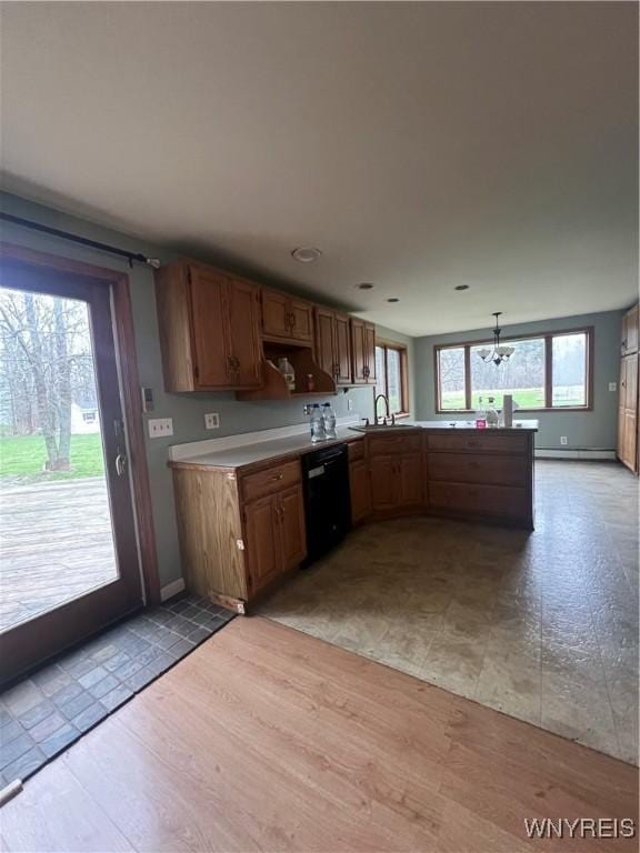 kitchen featuring a sink, light countertops, a peninsula, a notable chandelier, and black dishwasher