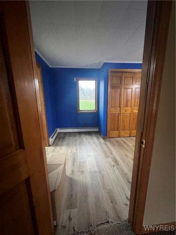 unfurnished bedroom with light wood-type flooring, baseboard heating, baseboards, and crown molding