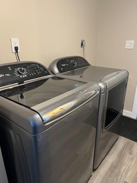 washroom with light wood finished floors, washing machine and clothes dryer, and laundry area