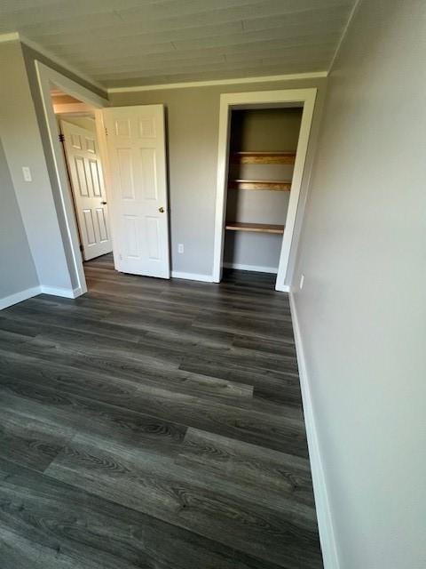 unfurnished bedroom with a closet, baseboards, and dark wood-style flooring