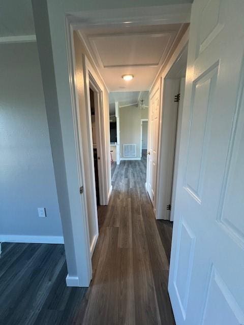 hall featuring baseboards, visible vents, and dark wood finished floors