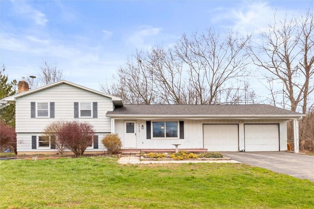 split level home featuring an attached garage, driveway, a chimney, and a front yard
