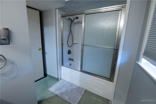 bathroom featuring bath / shower combo with glass door and baseboards