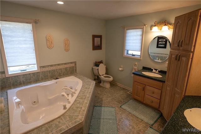 full bathroom featuring toilet, a whirlpool tub, a wealth of natural light, and vanity