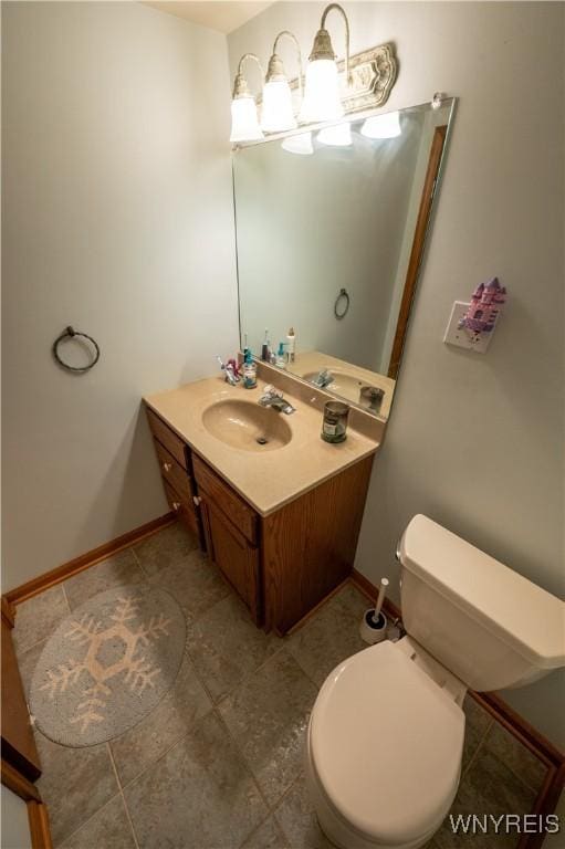 half bath featuring baseboards, toilet, and vanity