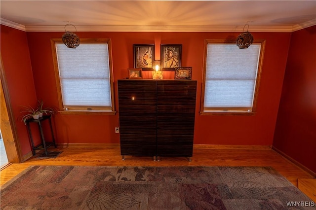 interior space with wood finished floors, crown molding, and baseboards