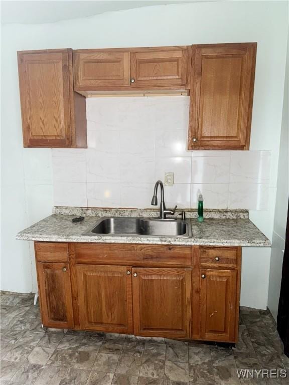 720 Sherman St, Buffalo, NY 14211 - kitchen featuring light stone countertops, a sink, brown cabinets, and tasteful backsplash
