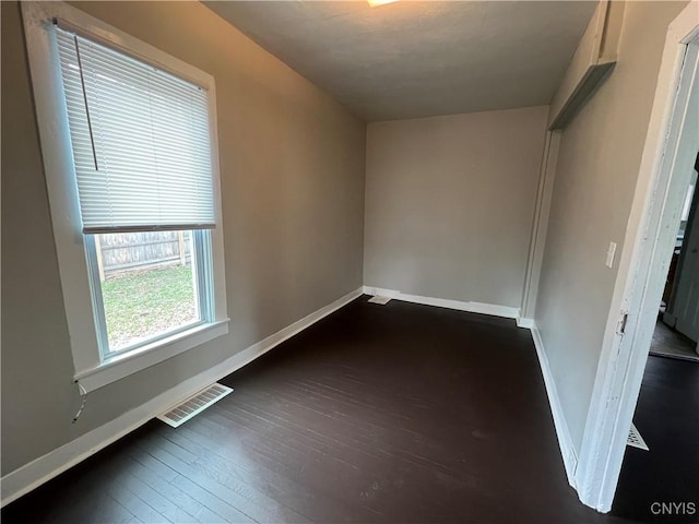 empty room with dark wood-style floors, baseboards, and visible vents
