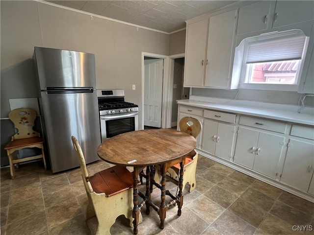kitchen featuring light countertops, stone finish flooring, white cabinetry, and stainless steel appliances
