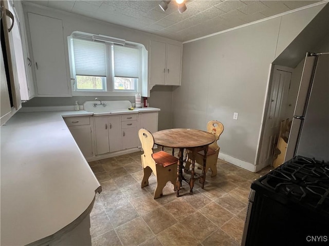 kitchen featuring a ceiling fan, a sink, gas range, light countertops, and white cabinets