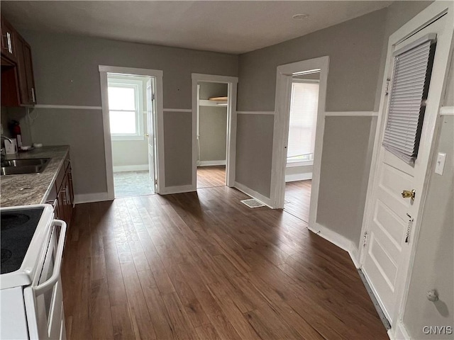 kitchen featuring baseboards, a sink, dark wood finished floors, and electric range