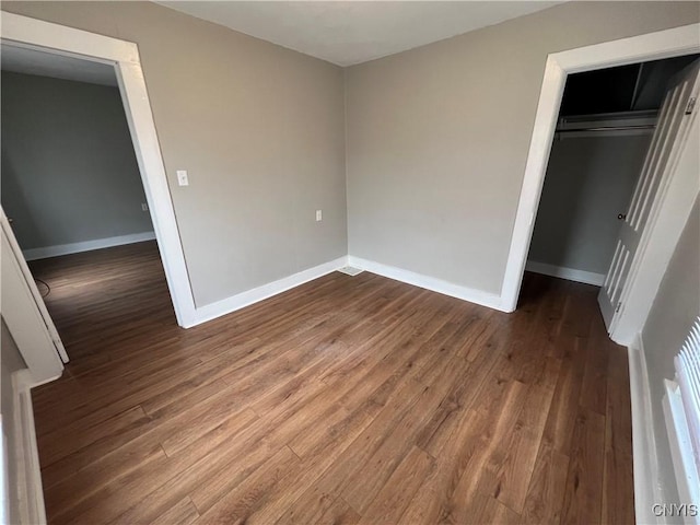 unfurnished bedroom with wood finished floors, a closet, and baseboards