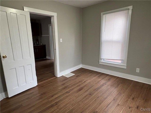 empty room with visible vents, baseboards, and dark wood-style floors