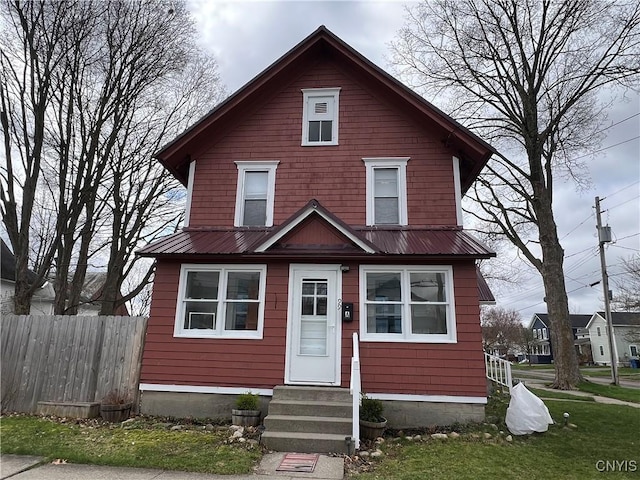 traditional style home featuring entry steps, metal roof, and fence