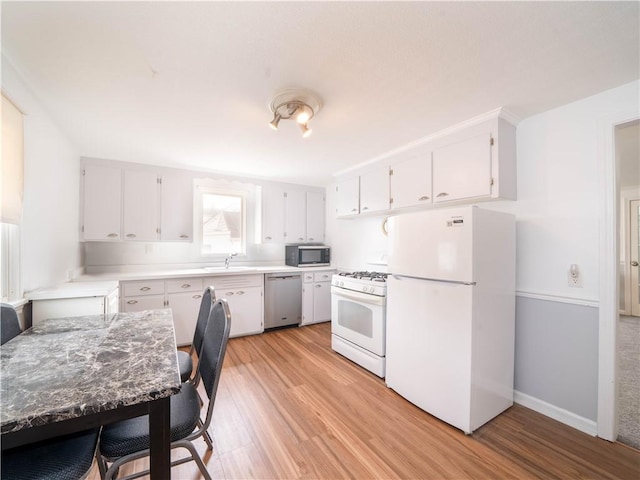 kitchen featuring a sink, light wood-style flooring, light countertops, white cabinets, and appliances with stainless steel finishes